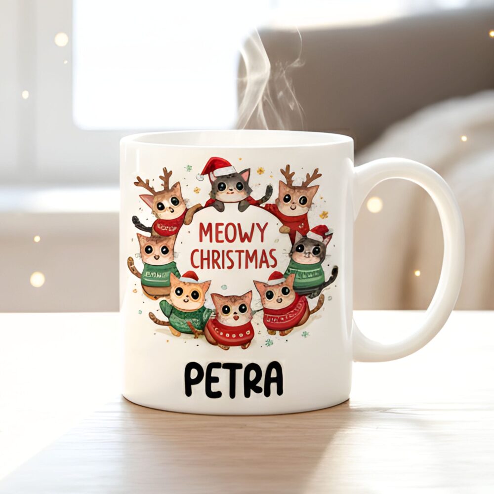 Keramična skodelica s pisanimi ilustracijami mačk v božičnih kapah. Glavni napis je "Meowy Christmas".