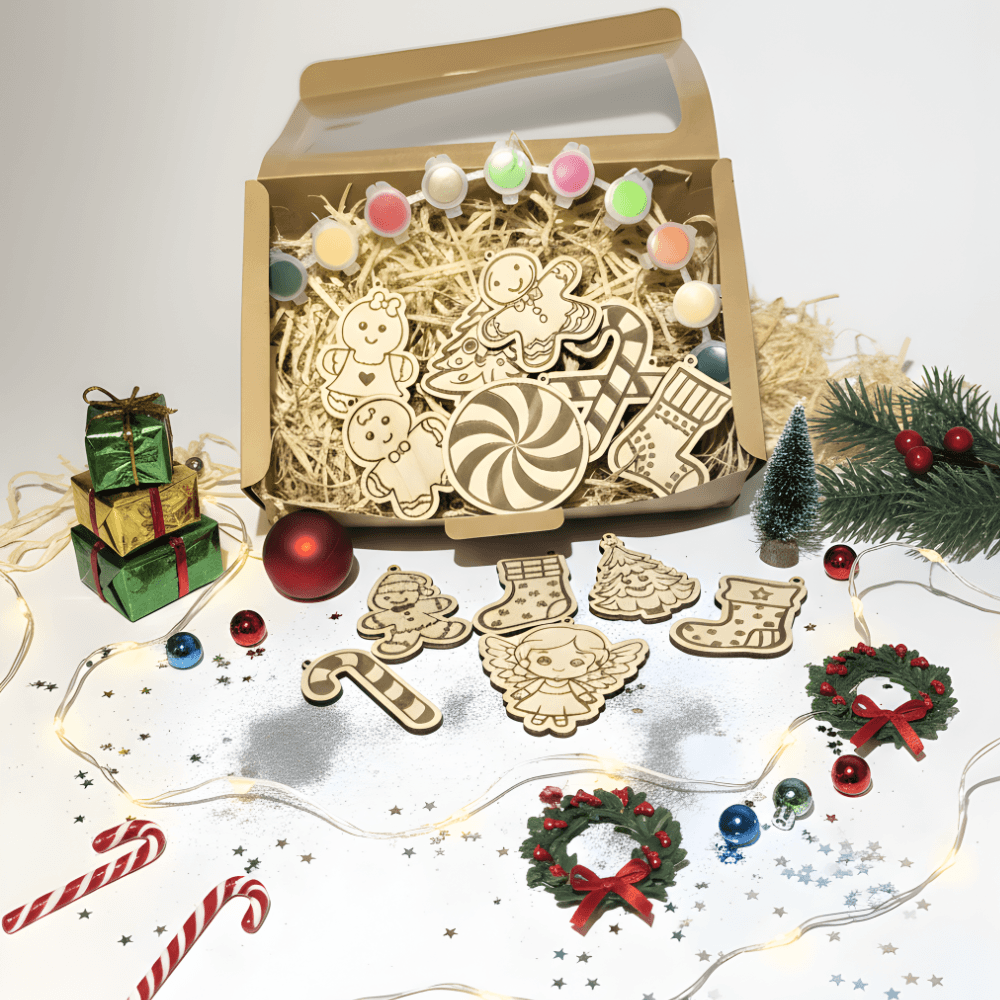 Božični ustvarjalni komplet v odprti kartonski škatli s prozornim pokrovom. Znotraj škatle so leseni izrezki božičnih motivov (medenjaki, sladkorne palice, škorenjčki) in posodice z barvami, vse postavljeno na slamo. Pred škatlo so dodatni leseni izrezki (medvedek, škorenjčki, jelke, angel, sladkorna palica) in različni božični okraski: trije majhni darilni paketi, rdeča božična kroglica, majhno umetno božično drevesce, vejica iglavcev z rdečimi jagodami, dva miniaturna božična venca, razmetane božične kroglice, bleščice, zvezdice in lučke. V spodnjem levem kotu sta dve rdeči sladkorni palici. Vsi elementi so postavljeni na beli podlagi.