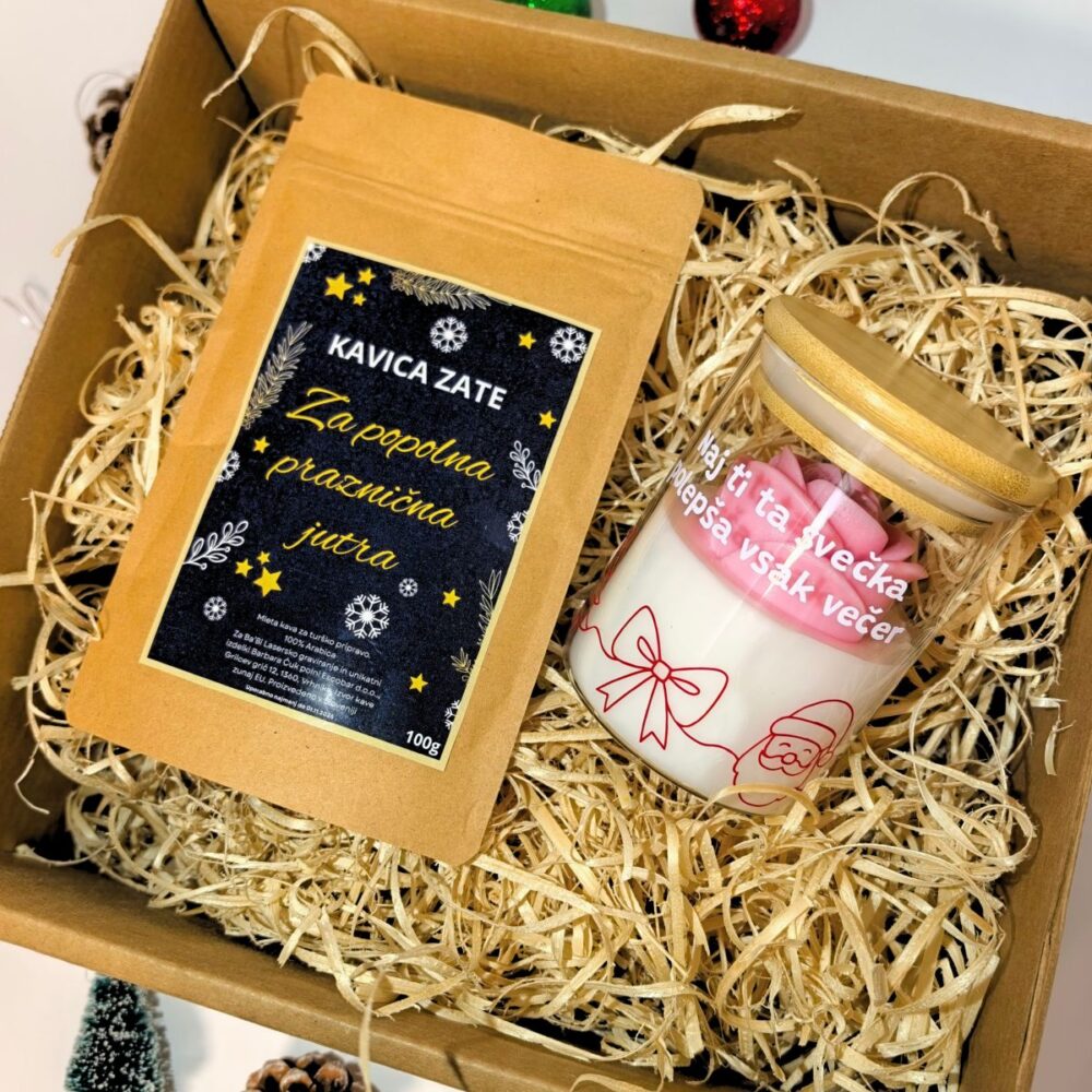 Darilni paket v naravni kartonski škatli, napolnjeni s slamo, ki vsebuje 100g vrečko kave z napisom "Kavica za popolna praznična jutra" in dišečo svečko v steklenem kozarcu z roza cvetom in prazničnim motivom