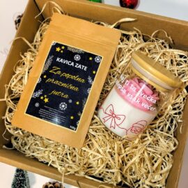 Darilni paket v naravni kartonski škatli, napolnjeni s slamo, ki vsebuje 100g vrečko kave z napisom "Kavica za popolna praznična jutra" in dišečo svečko v steklenem kozarcu z roza cvetom in prazničnim motivom