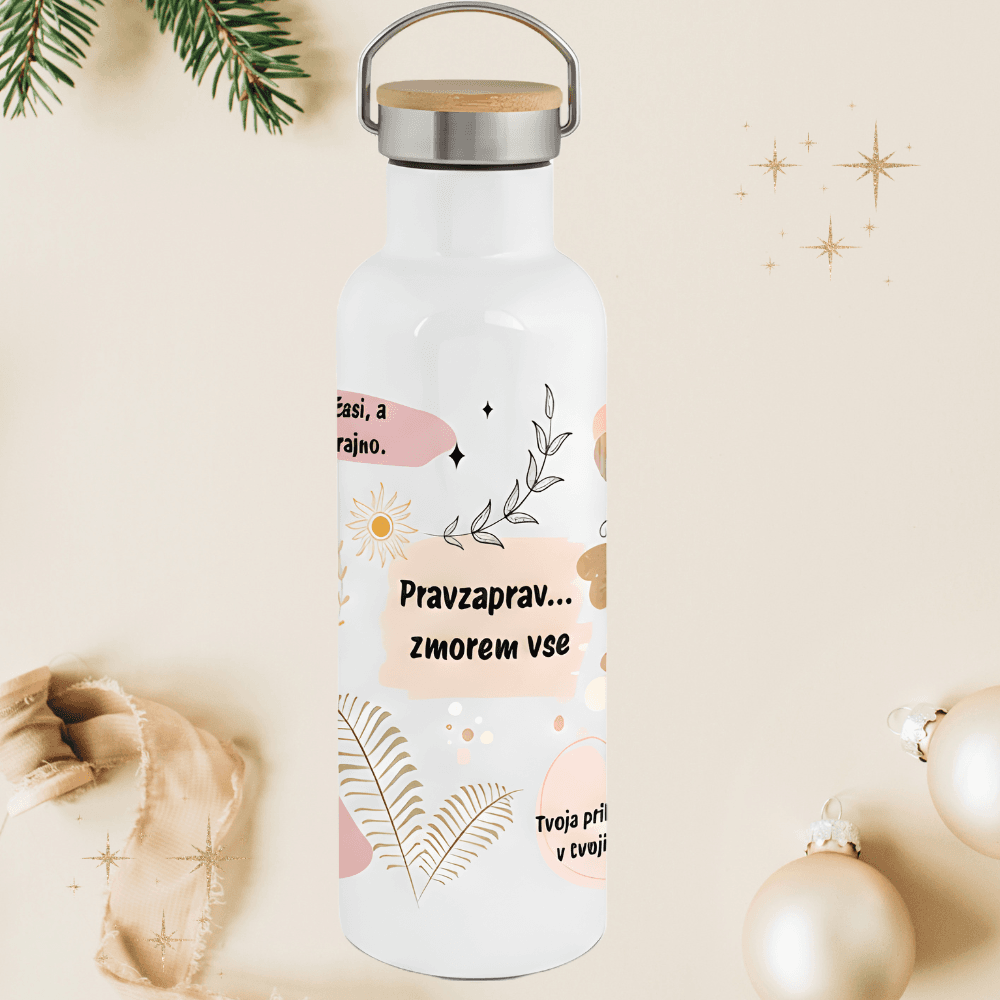 Bela termo steklenica z motivacijskim citatom 'Pravzaprav... zmorem vse', okrašena z nežnimi roza in bež vzorci. Steklenica je postavljena v praznični ambient z božičnimi bunkicami in smrekovimi vejicami.