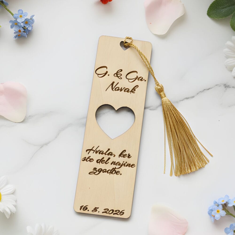 Personalizirano leseno knjižno kazalo z izrezanim srčkom, zlato resico in vgraviranim napisom G. & Ga. Novak, postavljeno na marmorno podlago s cvetjem kot unikatno darilo za svate.