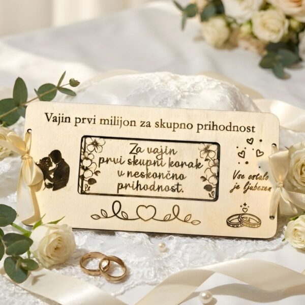 Personalizirana lesena čestitka za denar z vgraviranim napisom "Vajin prvi milijon", obdana z belimi vrtnicami, biseri in zlatimi poročnimi prstani.