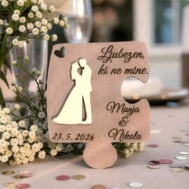 Bližnji posnetek lesene puzzle z vgraviranima imenoma Manja in Nikola ter datumom, ki prikazuje detajle gravure in naraven les.