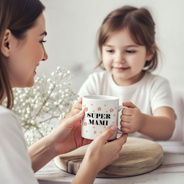 Nasmejan otrok podaja mami cvetlično skodelico z napisom 'Super mami', kar prikazuje trenutek obdarovanja za materinski dan.