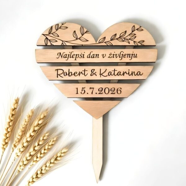 Leseni poročni topper za torto v obliki srca z vgraviranimi oljčnimi vejicami, napisom "Najlepši dan v življenju", imenoma Robert & Katarina ter datumom poroke, obdan s klasjem pšenice.