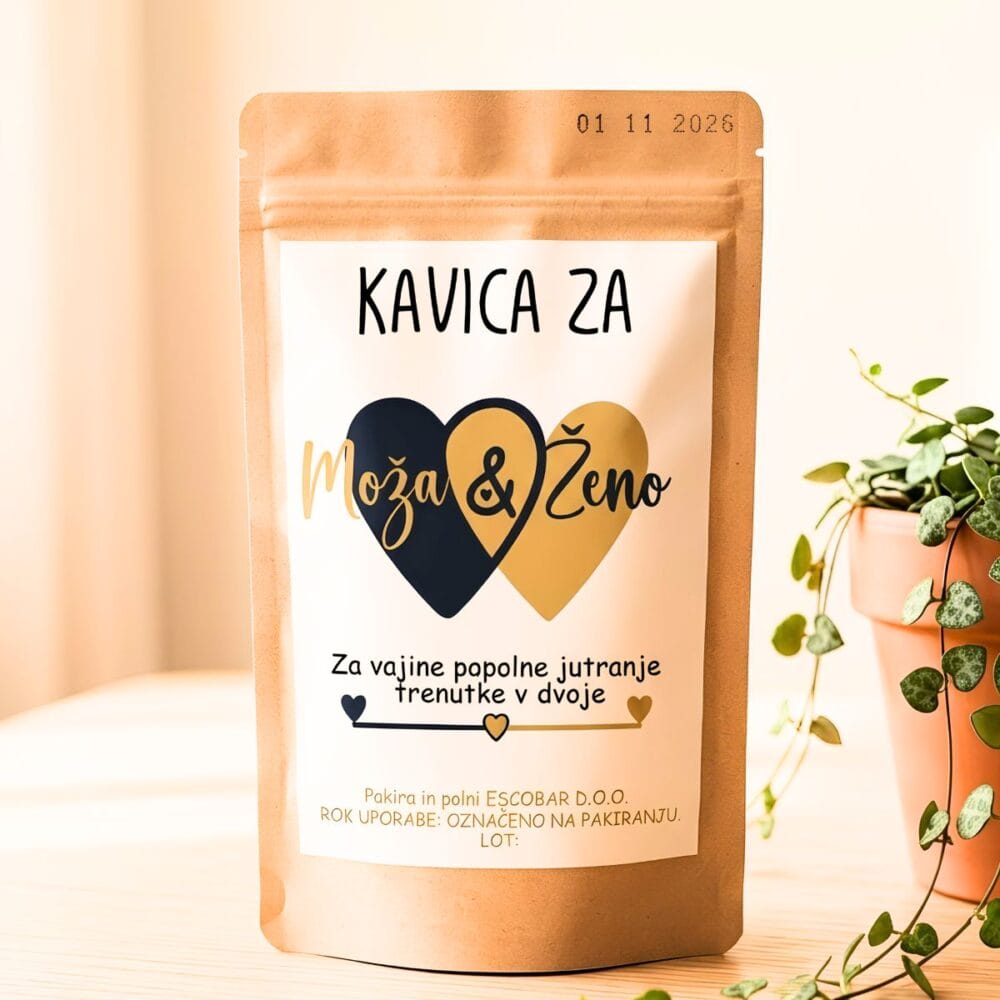 Rjava aroma zaščitna vrečka poročne kave »Kavica za Moža & Ženo«. Na beli etiketi sta dve prepleteni srci v črni in zlati barvi ter napis: »Za vajine popolne jutranje trenutke v dvoje«. V ozadju je lončnica.