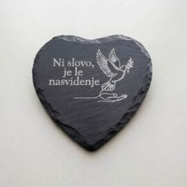 Spominski kamen - Ni slovo Spominski kamen v obliki srca iz črnega skrilavca z belo gravuro dlani, goloba in napisom Ni slovo, je le nasvidenje