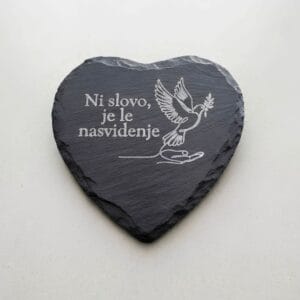 Spominski kamen v obliki srca iz črnega skrilavca z belo gravuro dlani, goloba in napisom Ni slovo, je le nasvidenje